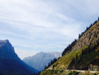 A red bus cruises along the Going-to-the-Sun Road. 